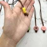 A hand holds up the side of a yellow Small Flower Silicone Chewy Fidget Necklace.
