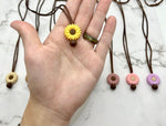 A hand holds up a yellow Small Flower Silicone Chewy Fidget Necklace.