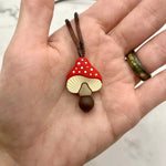 A hand holding the red Spotted Mushroom  Fidget Chewable Jewelry Necklace.