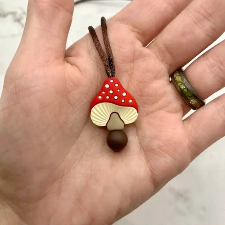 A hand holding the red Spotted Mushroom  Fidget Chewable Jewelry Necklace.
