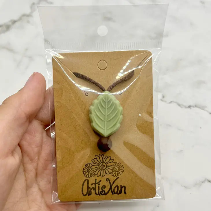 The Sage Green Textured Leaf Fidget Chewable Jewelry Necklace in its product package.
