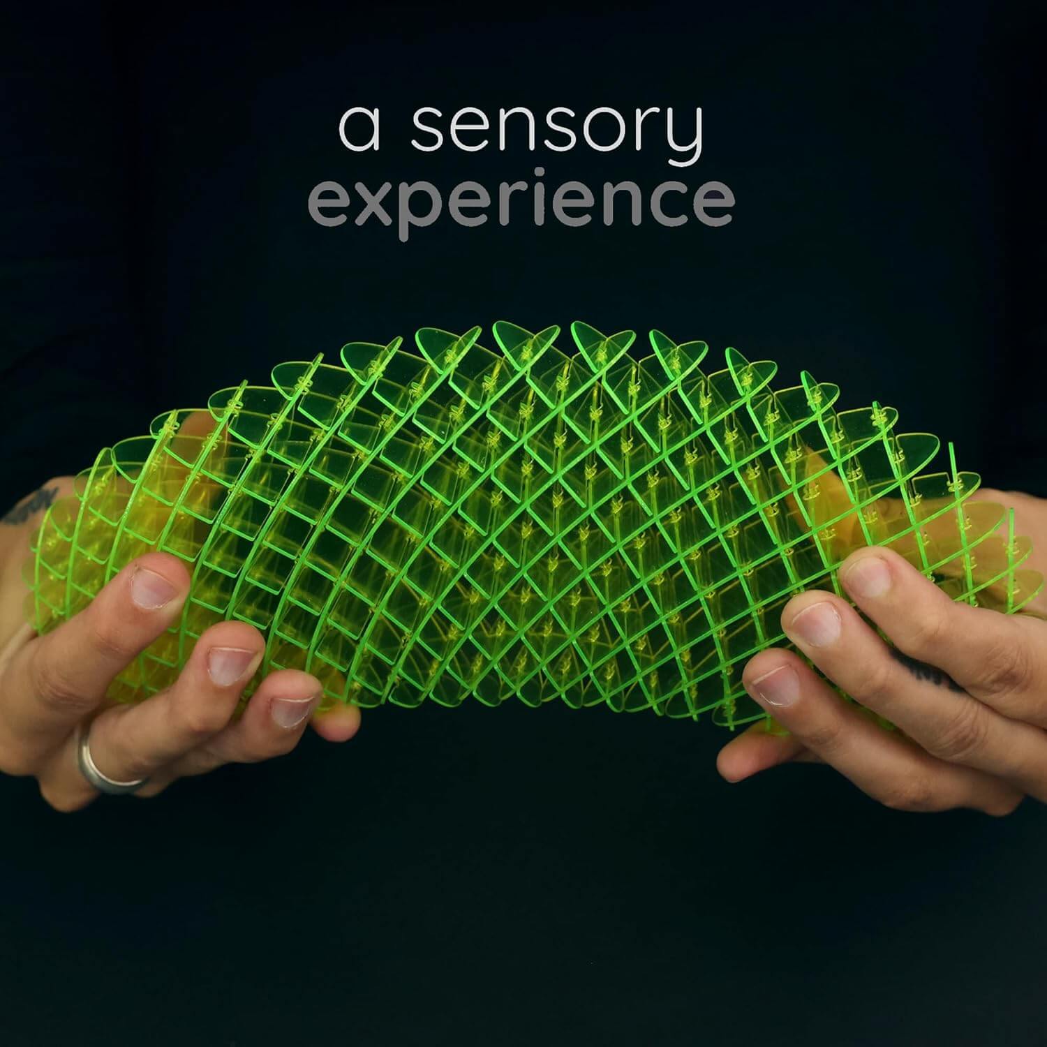 Two hands expand the Big Green Morf Fidget Worm.