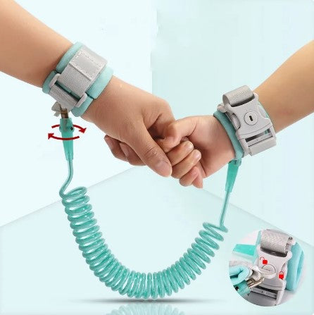 An adult hand with light skint one holds out two fingers that are being grabbed by a much smaller hand with light skin tone. The hands are wrapped in the blue Safety Wrist Tether with the Child Lock. In the bottom right corner there is a picture demonstrating how the key is used to open the Child Lock.