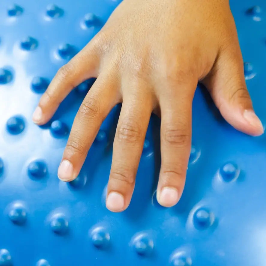 A hand touches the tactile bumps on the Peanut Stability Ball.