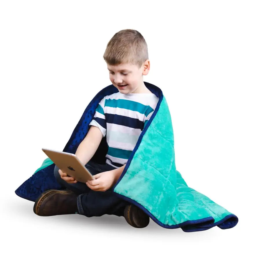 A child looks at a tablet while wrapped in the Bouncyband Kids Soft Fleece Sensory Weighted Blanket - 7 lb.
