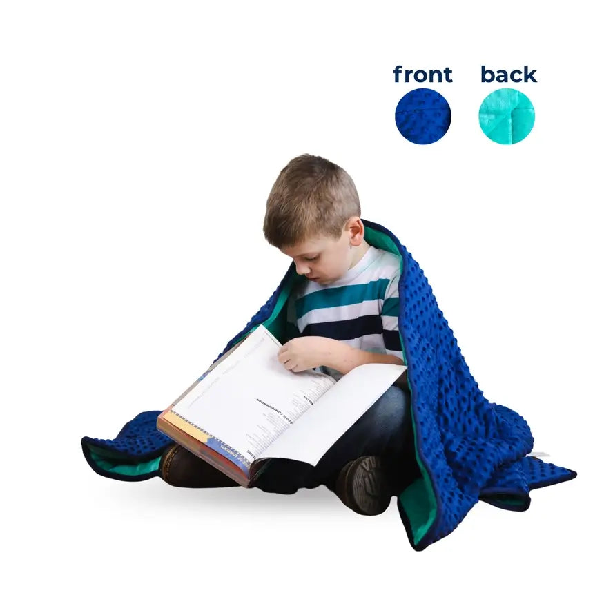 A child looks through a school book while wrapped in the Bouncyband Kids Soft Fleece Sensory Weighted Blanket - 7 lb.