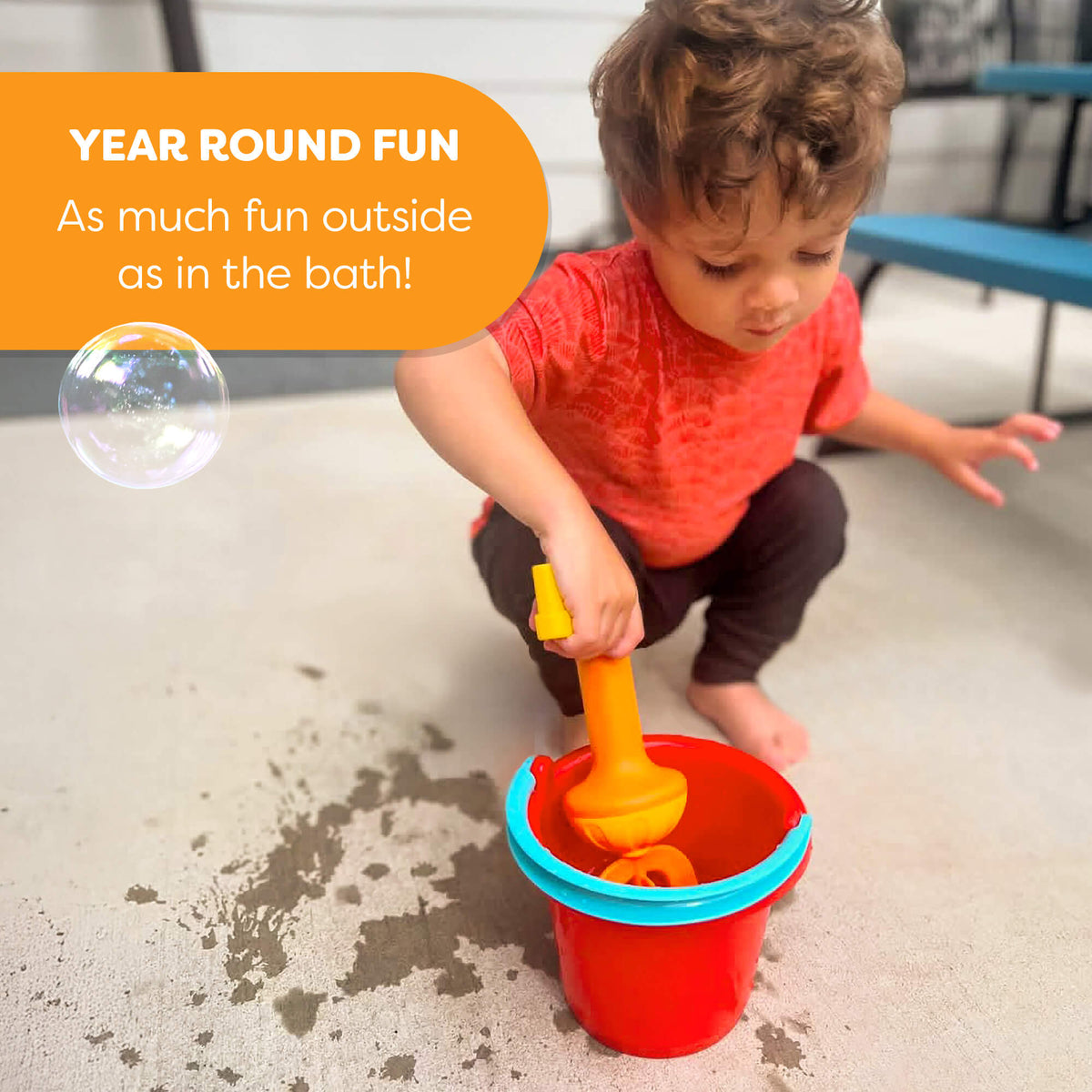 A child puts the Bubble Bath Whisk in a bucket on an outside patio and makes a splash.