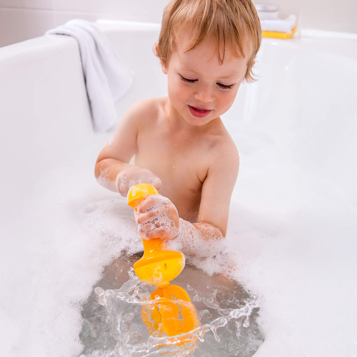 A child turns the crank on the Bubble Bath Whisk in Yellow, mixing up the bubbles.