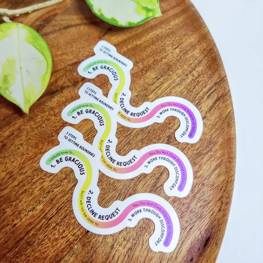 Three Setting Boundaries Vinyl 3" Stickers sit on a wooden table.