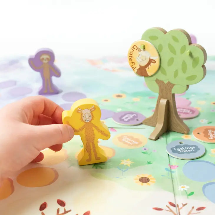 A small hand with light skin tone moves one of the pieces in the Feelings Adventure Board Game.