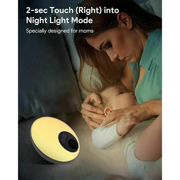 A baby is being nursed a the White Noise Lamp with Clock provides a warm light for mom.