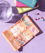 The peach Crush Everything's Fine Pill and Vitamin Case, full of pills and covered in identifying stickers.