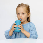 A child sips from the EZPZ Blue Straw + Cup System for Toddlers.