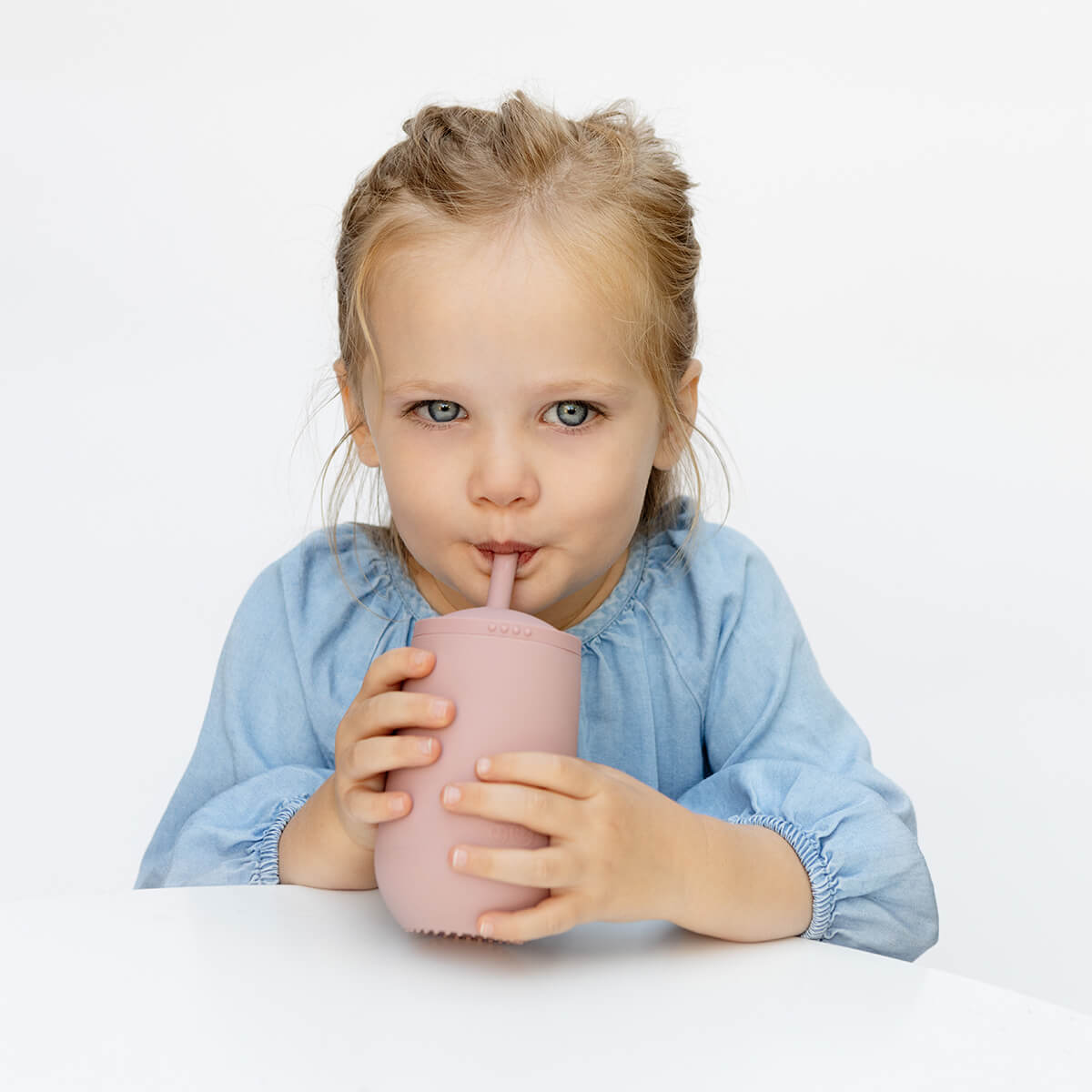 A child drinks from the EZPZ Blush Cup + Straw System.
