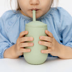 A child drinks from the EZPZ Sage Cup + Straw System for Toddlers.