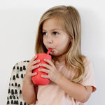 A child sips from the EZPZ Coral Cup + Straw System for Toddlers.