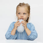 A child sips from the Pewter EZPZ Cup + Straw System.