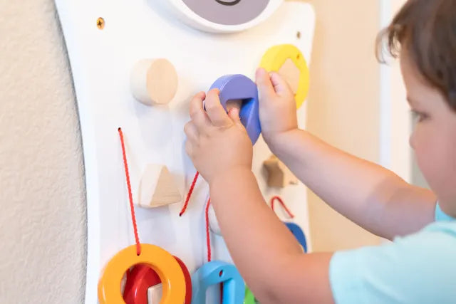 An up close look at a child with light skin tone putting on a shape onto the Zebra Activity Wall Panel.