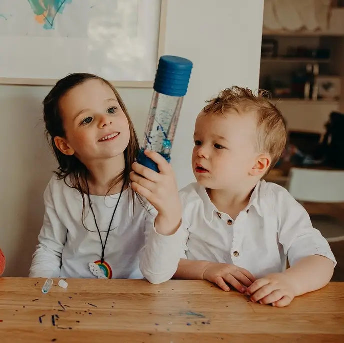 Two children look intently at the DIY Calm Down Sensory Bottle.