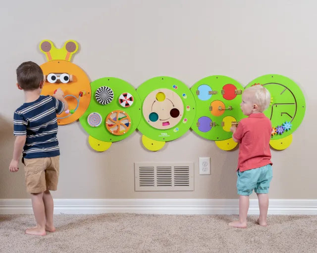 Two children play at either end of the Caterpillar Activity Wall Panel.