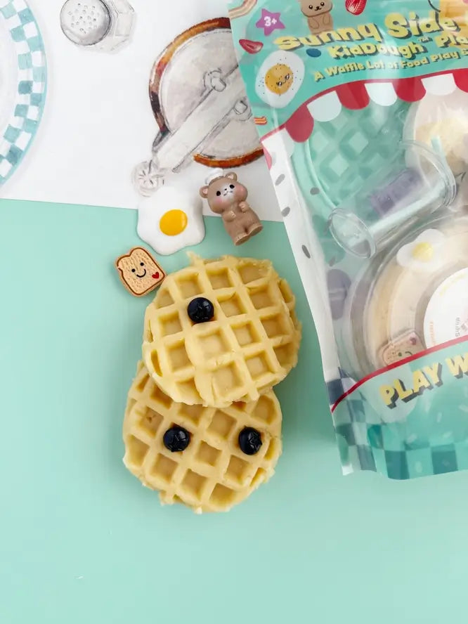 Two waffles covered in blueberries and the small bear chef.