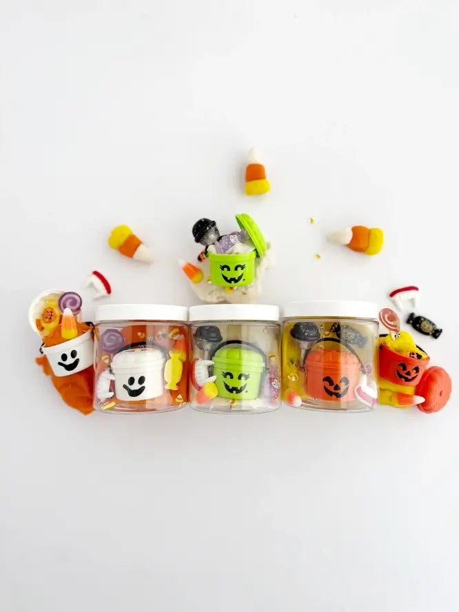 All three of the Trick or Treat Mini Dough-to-Go Kits are lined up next to one another. Their contents are spread in an arch above the product containers.