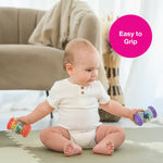 A baby lifts two My First Rainsticks like weights.