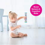 A toddler sits on the floor and holds the Rainstick 8" up.
