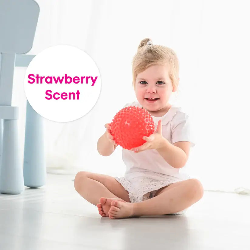 A child holds the red strawberry scented ball.