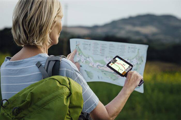 A woman holds the explore 5 over a map while on a hike.