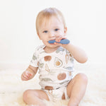 A baby puts the Indigo ezpz Baby-Led Toothbrush in its mouth.