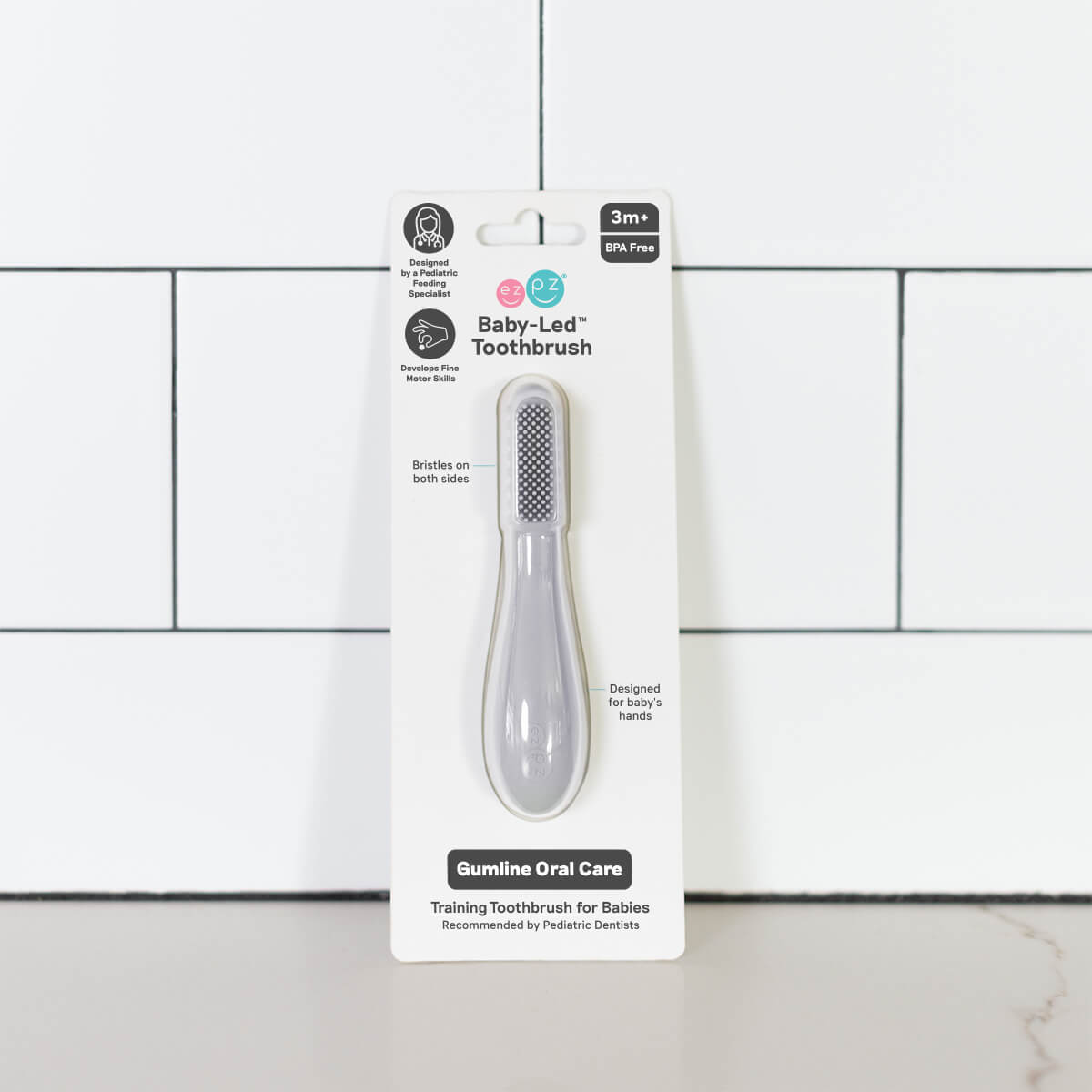 The Pewter ezpz Baby-Led Toothbrush in its product package.