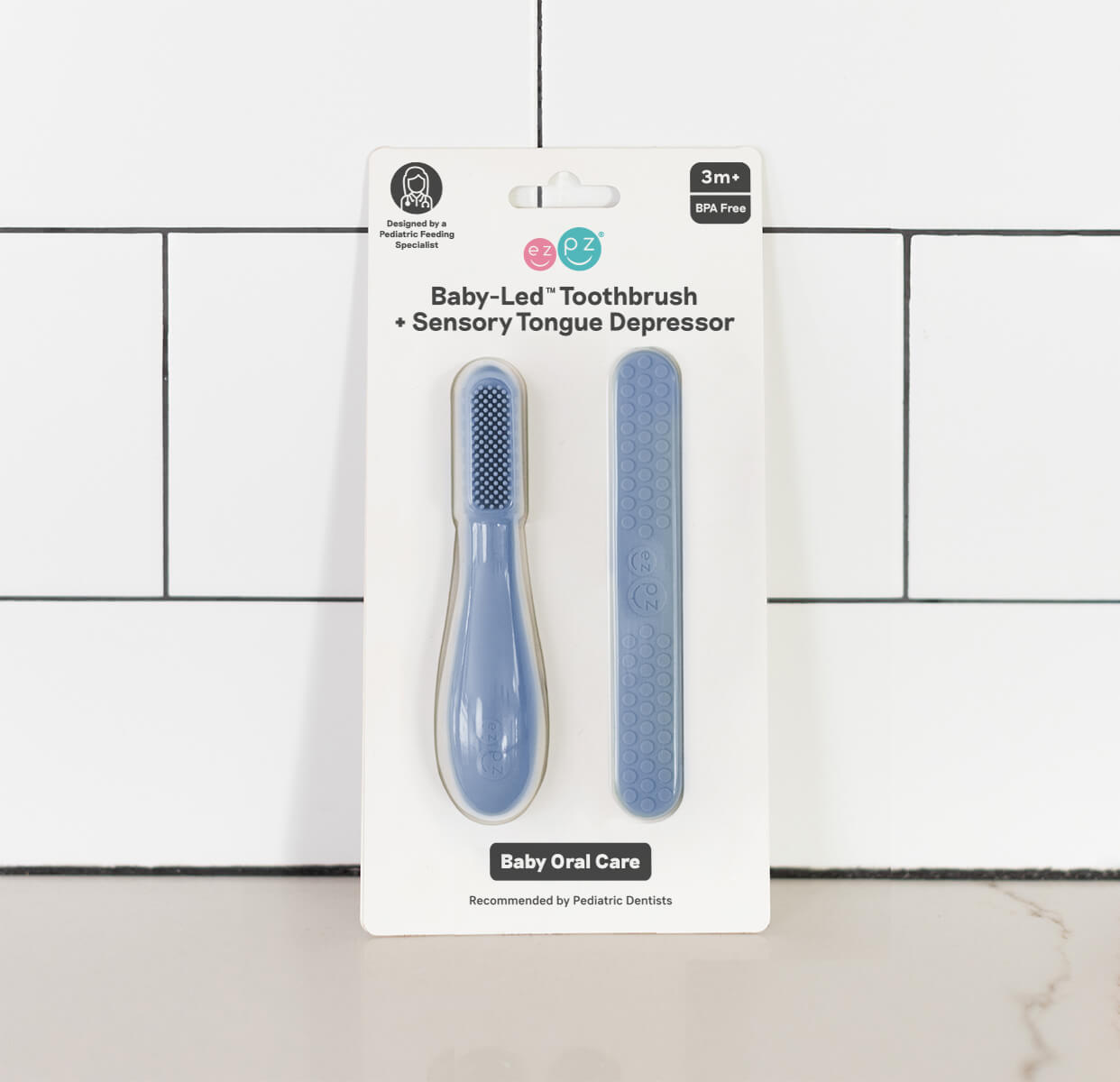 The Indigo ezpz Baby-Led Toothbrush and Tongue Depressor Combo in its product packaging.