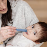 A woman puts the Indigo ezpz Tongue Depressor into a toddlers mouth.