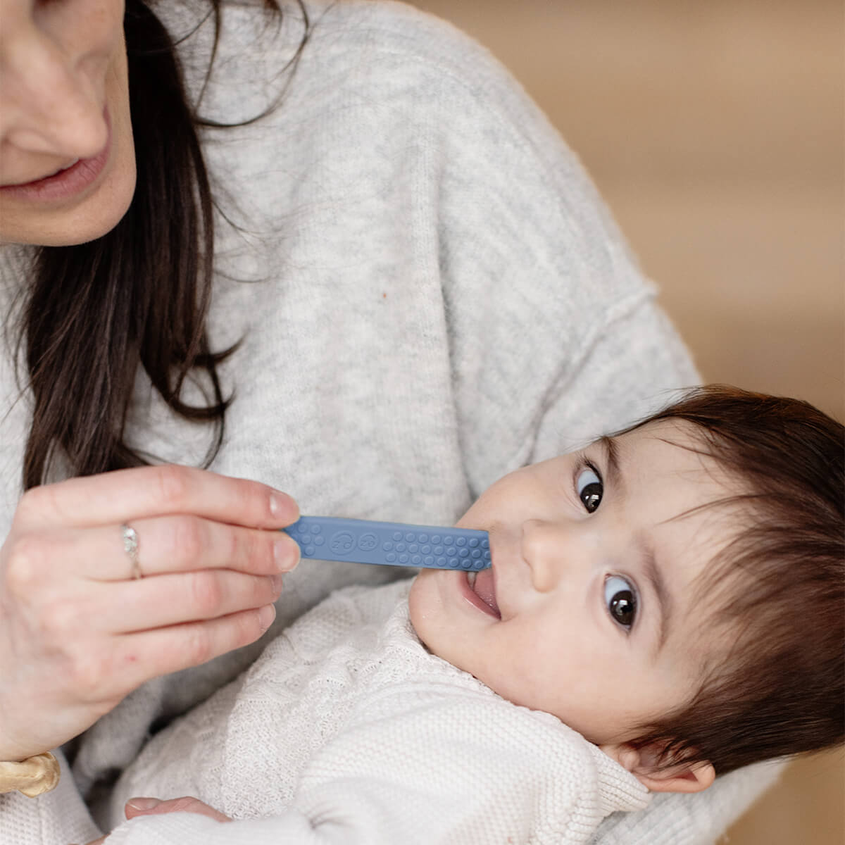 A woman puts the Indigo ezpz Tongue Depressor into a toddlers mouth.