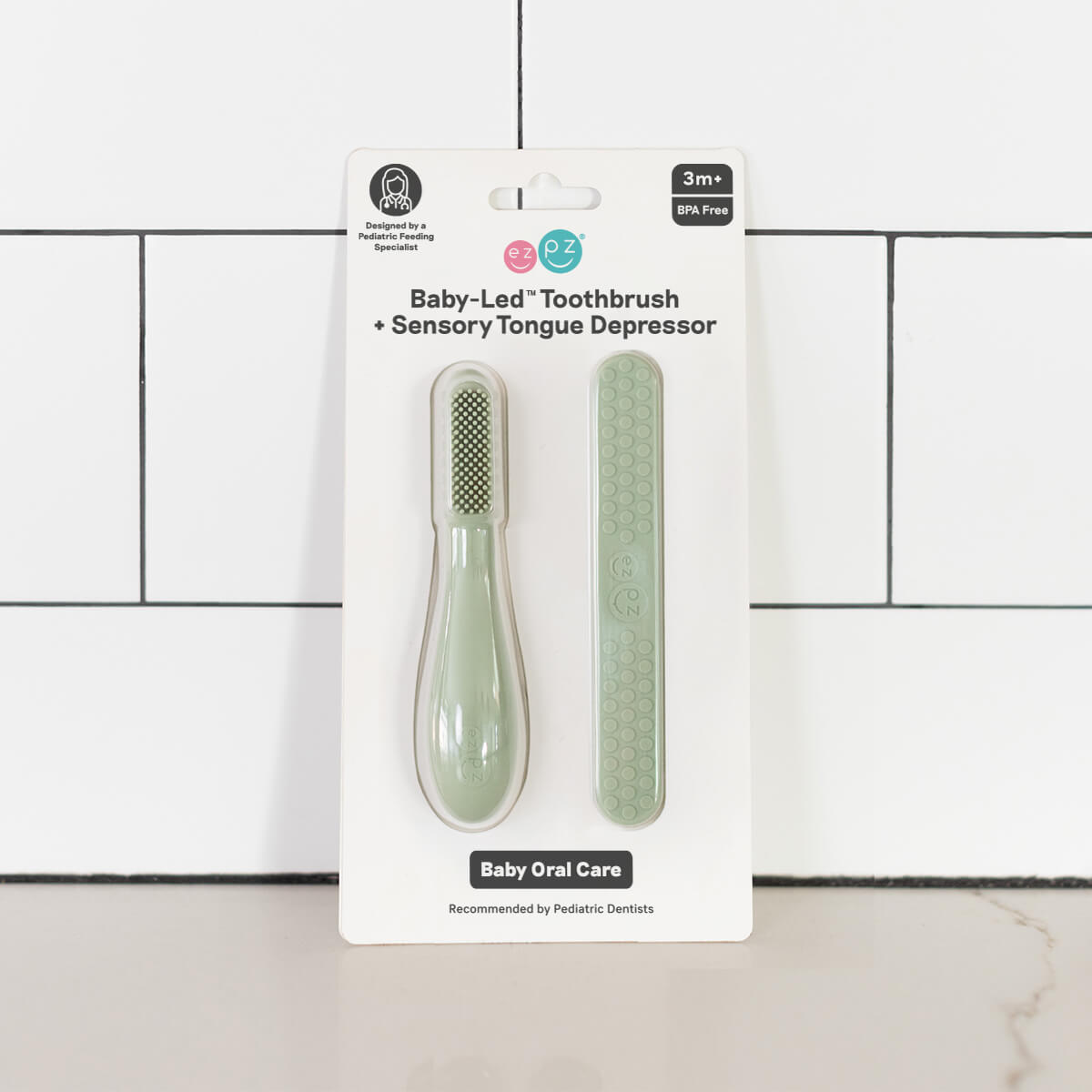 The Sage ezpz Baby-Led Toothbrush and Tongue Depressor Combo in its product package.