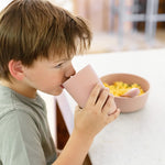 A child sips from the Blush 14 oz Cup + Lid with the lid removed.