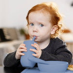 A toddler drinks from the Happy Cup and Straw System.
