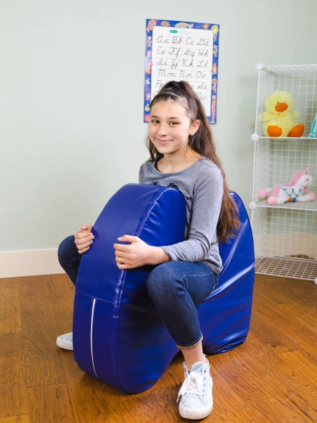 A child with light skin tone and a long brown ponytail sits inside of the Sensory Soft Squeeze Seat by Bouncyband like it is a pony.