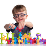 A child with glasses smiles and pushes the end pieces of the Squigz together.