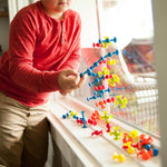 A child links Mini Squigz together that are adhered to a window.