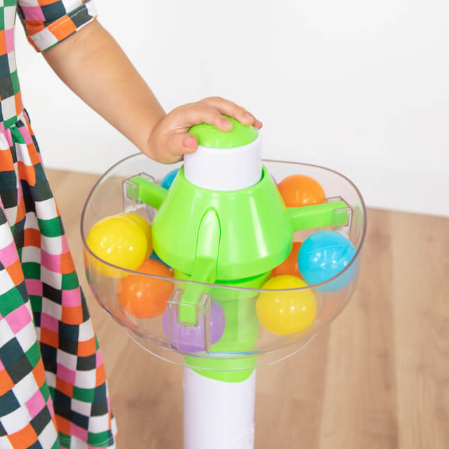 A child's hand pushes the button that releases the balls.