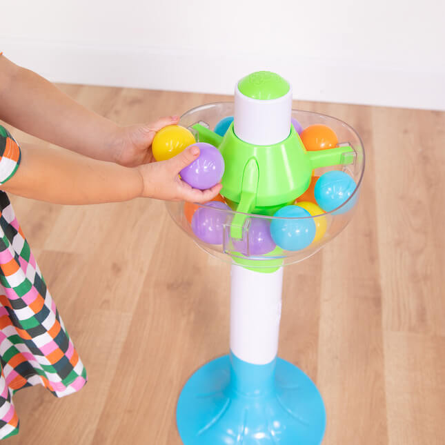 A child puts two colorful balls back into the SpillAgain tower.