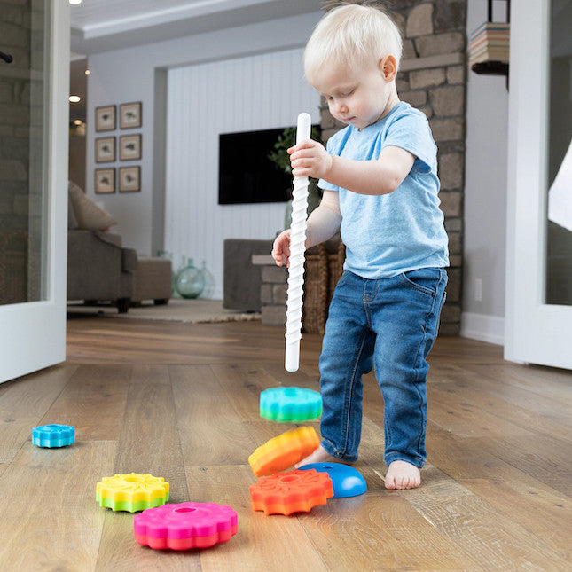 A child holding the spine of the Spin Again! while the colorful pieces drop onto the floor. 