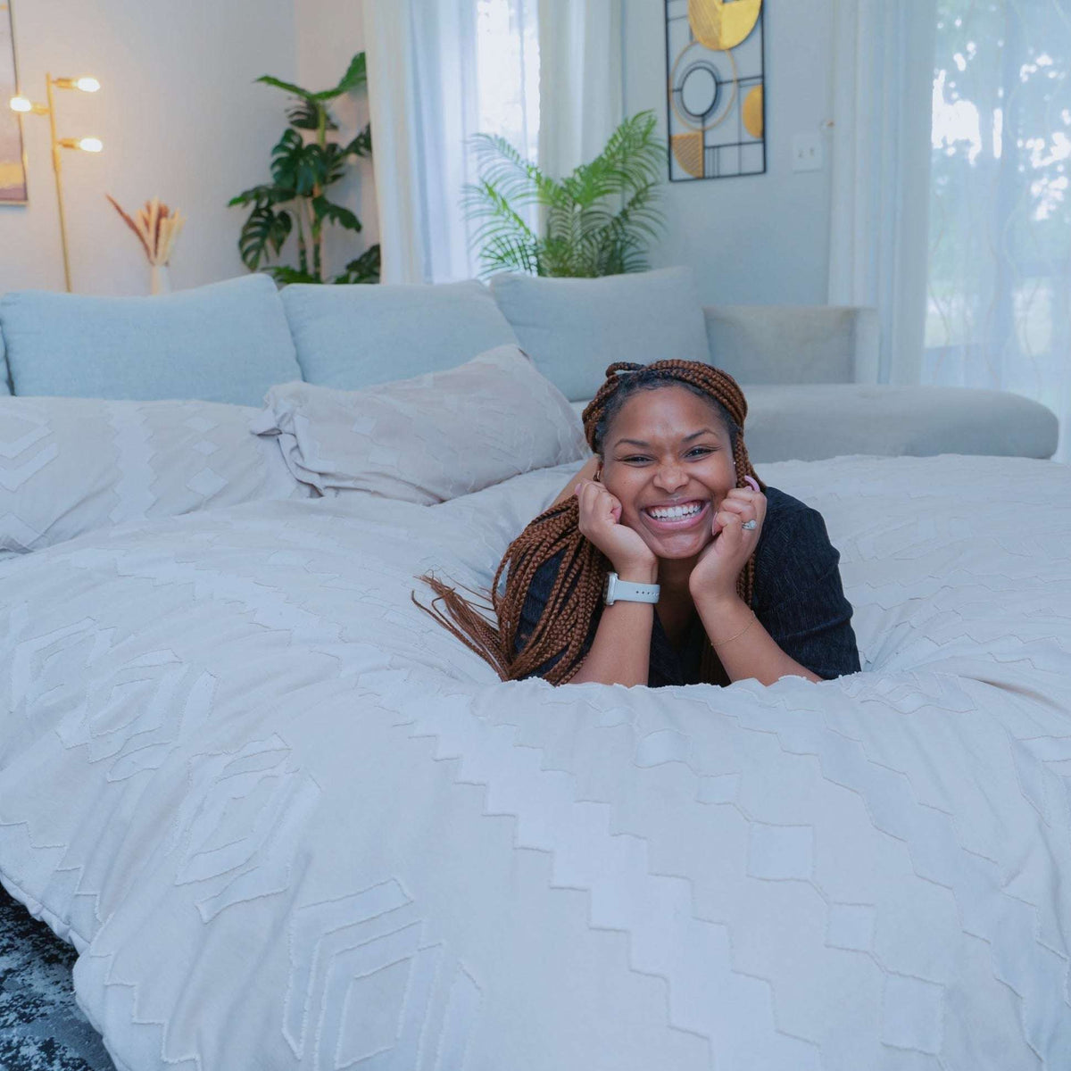 A woman lays on her stomach on the bed that is made up for sleeping.