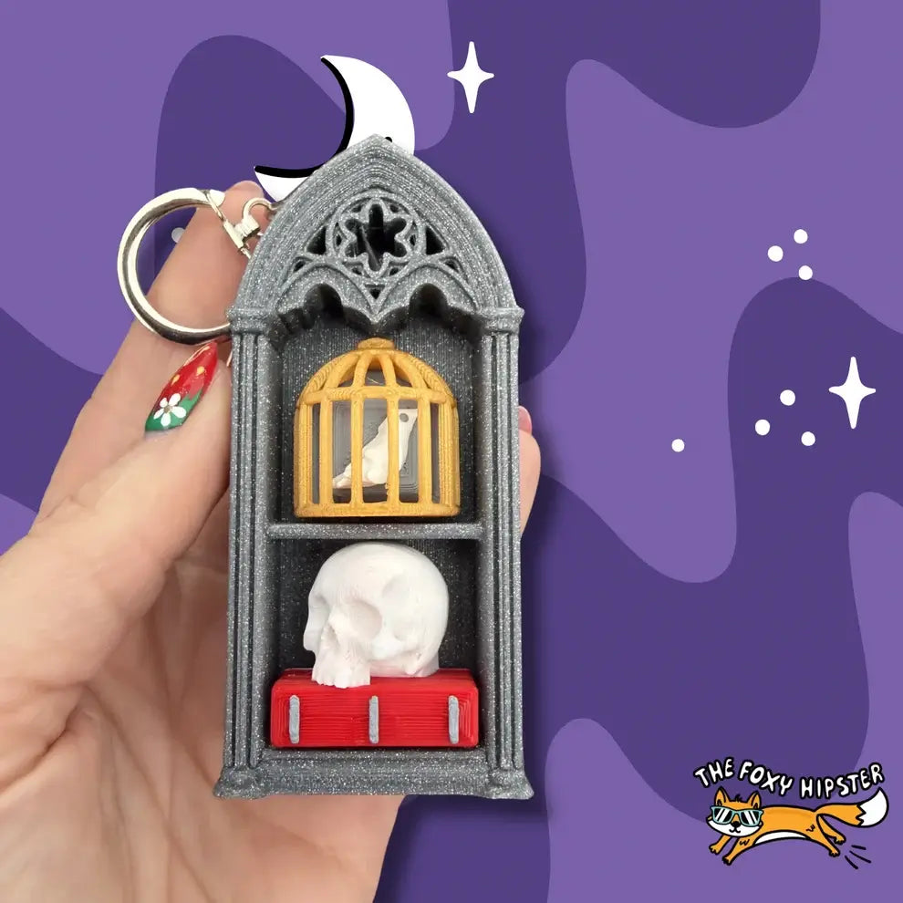 Birdcage and Skull Spooky Oddities Bookshelf Fidget Clicker Keychain.