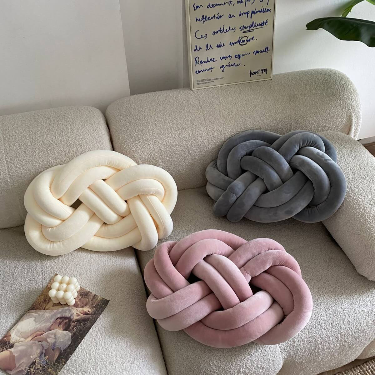 The Fried Dough Twist Plush Sensory Pillows on a cream colored couch.