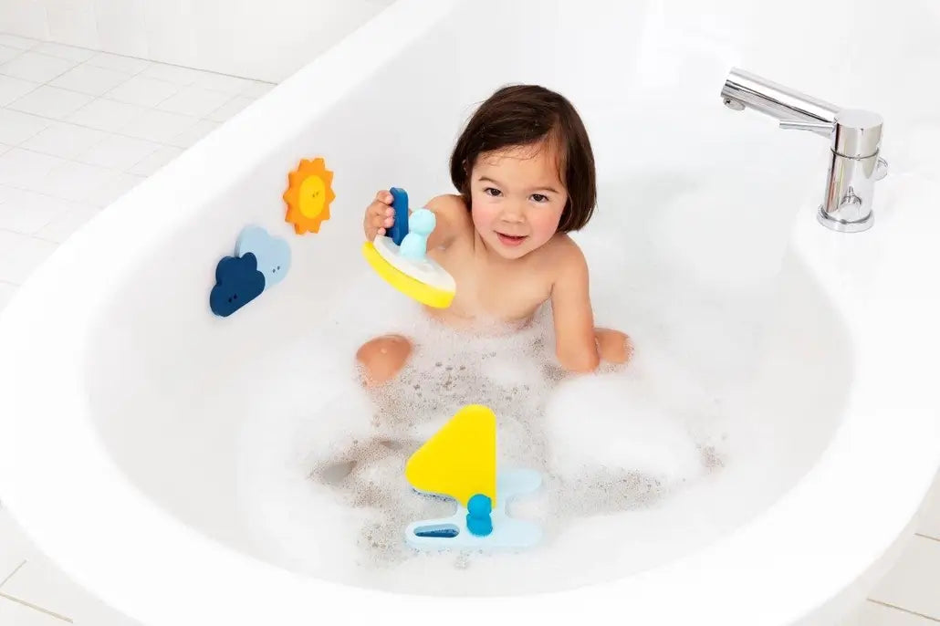 A child in the tub holds up a piece of Sail Away Bath Puzzle.