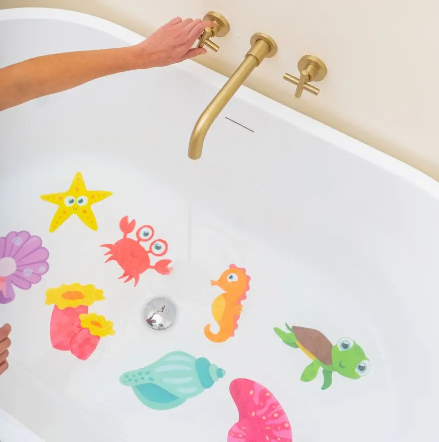 An adult hand turns the knob of the faucet on a tub lined with Guppy Grips - Glow-in-the-Dark.
