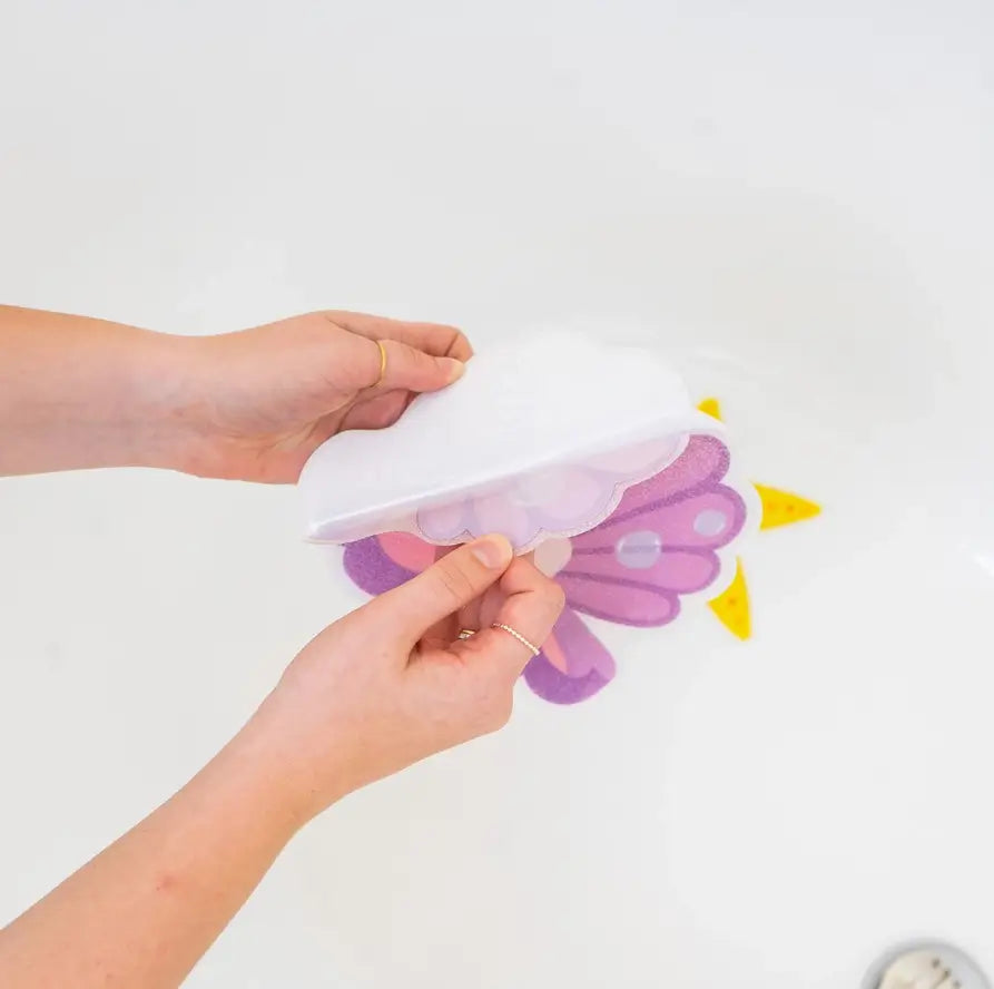 Two adult hands peel the sticky laminate away from the bottom of the clam Guppy Grip.